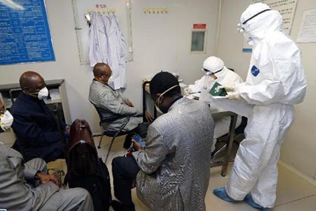 醫(yī)護(hù)人員穿戴埃博拉防護(hù)服、護(hù)目鏡及手套處理患者